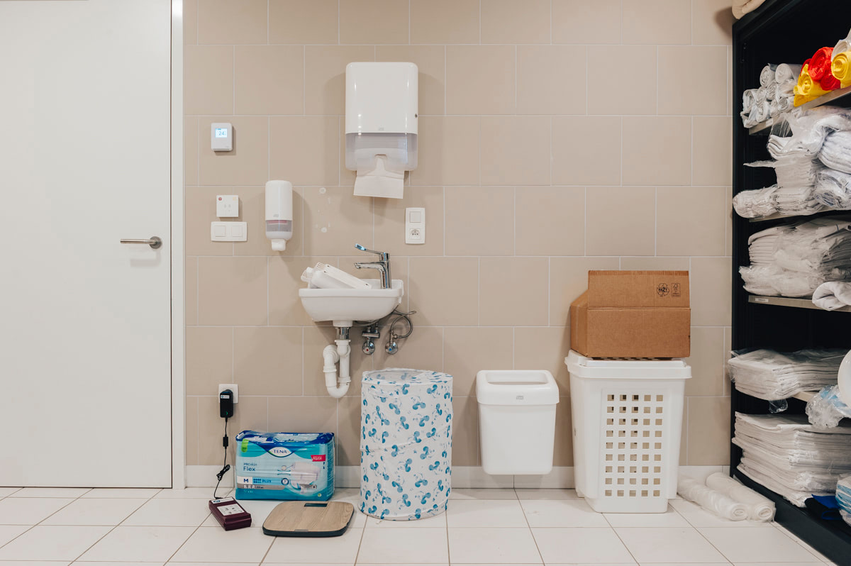 Gemeenschappelijke badkamer van WZC Mariaburcht vóór de herinrichting, met verzorgingsmateriaal en wasmanden