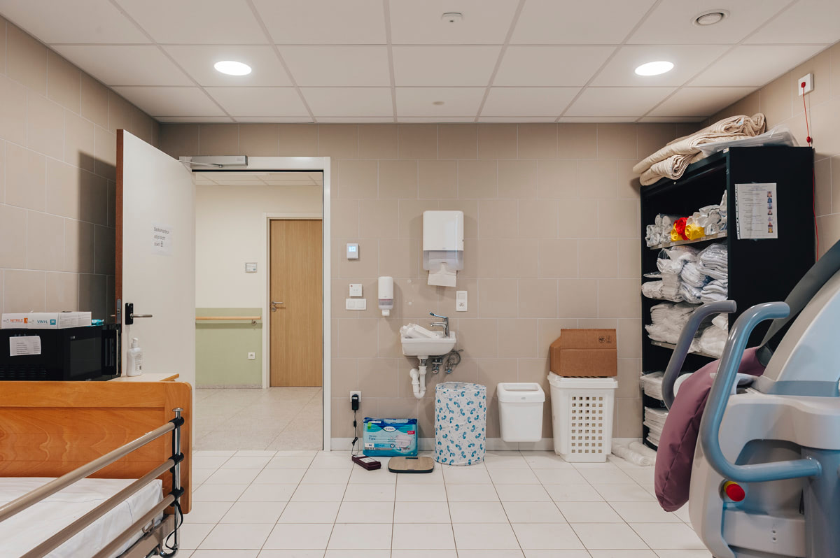 Overzicht van de gemeenschappelijke badkamer vóór de herinrichting, met opbergrekken en wasmanden