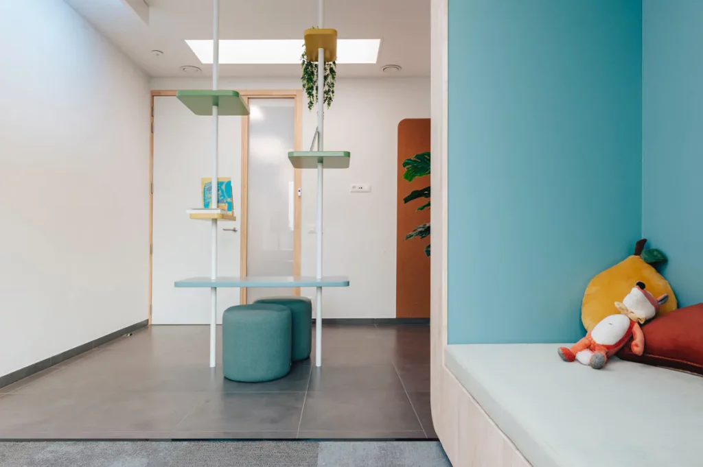 Wachtruimte voor kinderen met poef, hangplanten en zitbank met knuffels