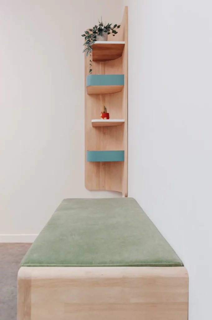 Houten zitbank met groen kussen en wandrek met blauwe accenten