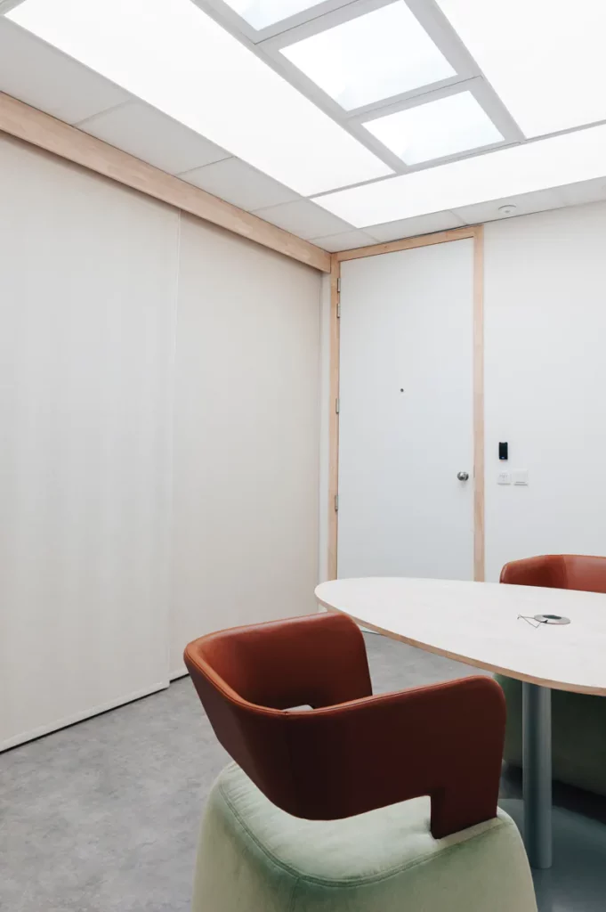 Videoverhoorkamer met verlicht plafond, tafel en fauteuils in warme kleuren